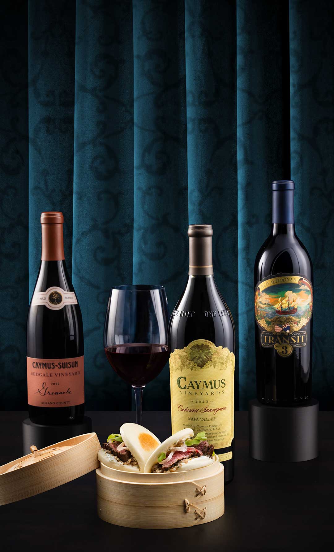 Eddie V's Caymus wine next to a wooden plate of handcrafted steak bao buns.